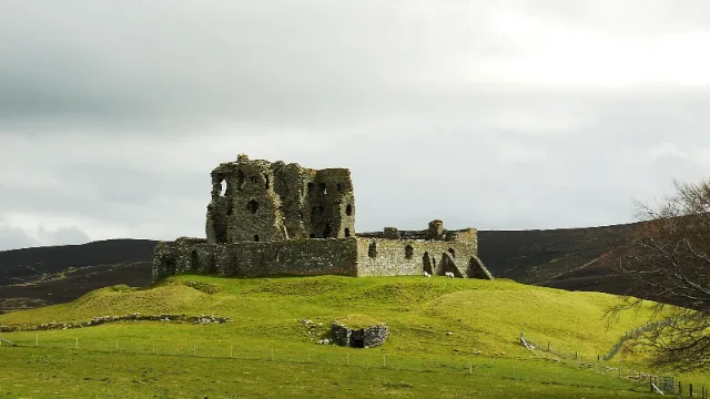 Auchindoun Castle: tower and outer wall on a grassy hillside