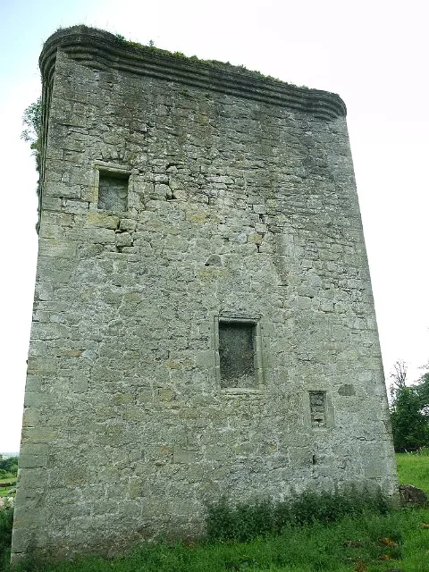 Steinmauer von Barr Castle in voller Höhe, mit zugemauerten Öffnungen und Gras am Fuß.