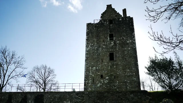 Kamienna wieża Cardoness Castle za niskim murem · Cardoness Castle