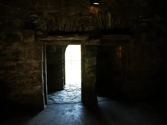 Widok z ciemnego sklepionego pomieszczenia ku otwartym drzwiom · Cardoness Castle