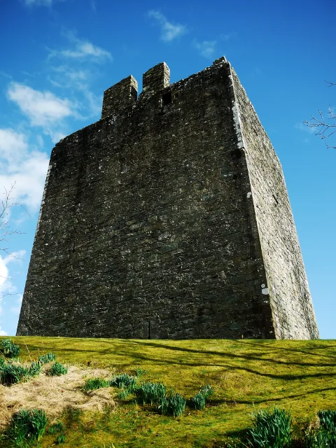 Dwie wysokie ściany wieży nad trawiastym zboczem · Cardoness Castle