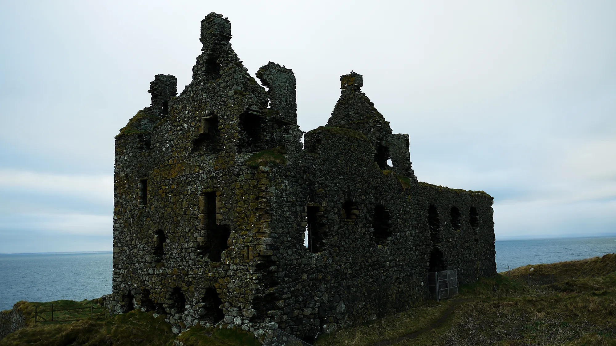 Ruinas de Dunskey Castle sobre un promontorio cubierto de hierba junto al mar