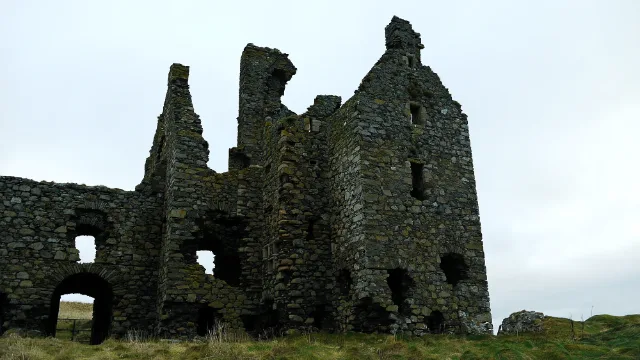 Muros de la torre y ala en ruinas de Dunskey Castle bajo un cielo nublado
