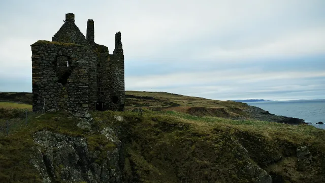 Dunskey Castle junto al mar abierto y la costa cubierta de hierba