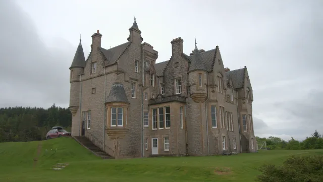 Steinmauern von Glengorm Castle mit vorspringenden Türmchen unter bewölktem Himmel