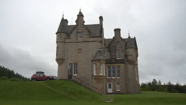 Schmale Seite von Glengorm Castle mit Türmchen über einem abfallenden Rasen