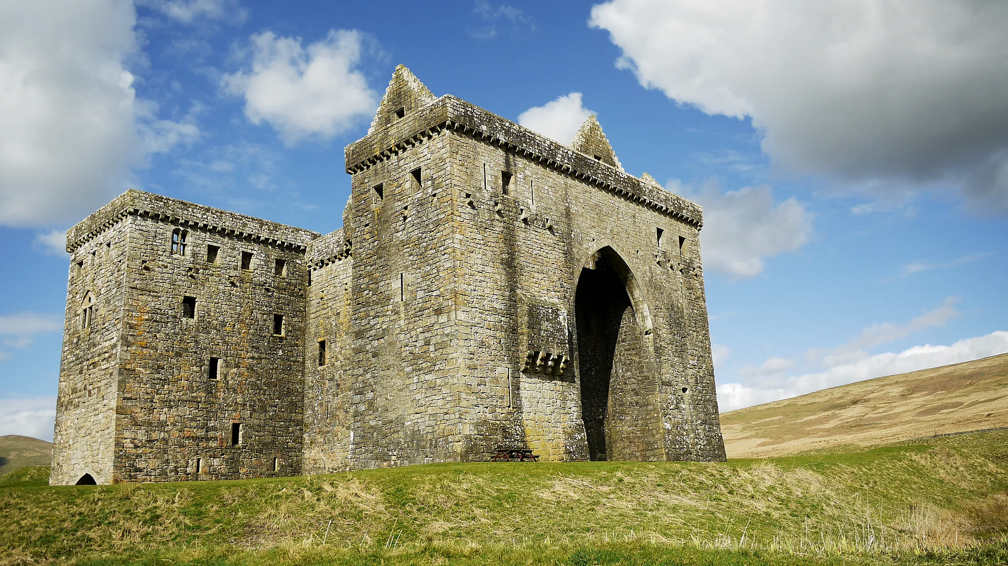 Hermitage Castle with its great arch and towers beneath a blue sky