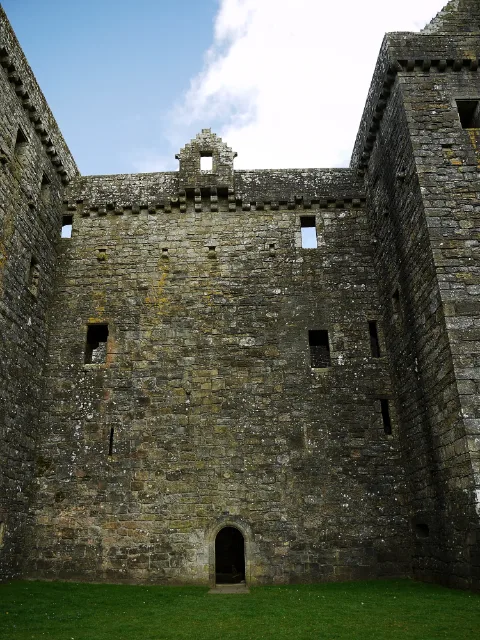 High stone wall and small arched doorway at Hermitage Castle